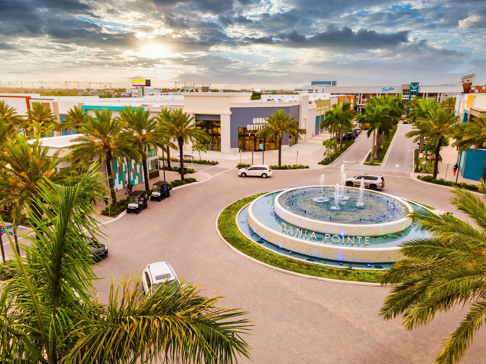 Fountain plaza and shops at the Dania Pointe mixed-use development at sunset