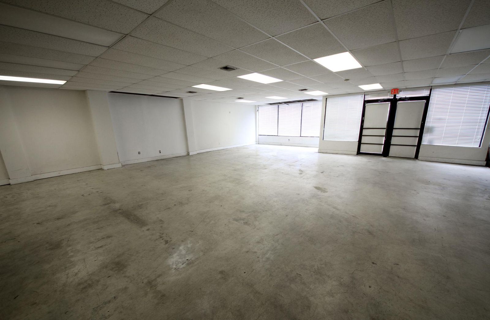 Open retail space with polished concrete floors, drop ceiling and storefront glass